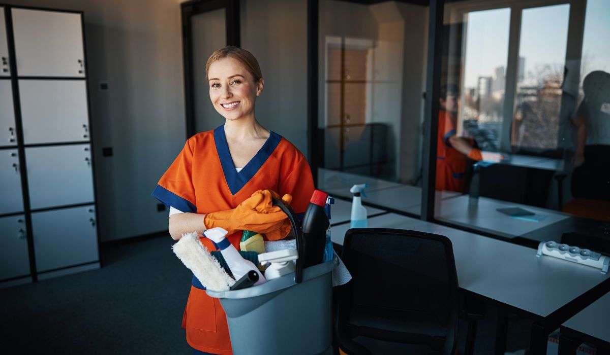Female cleaner in home environment holding a bucket of cleaning supplies, ready to start cleaning.