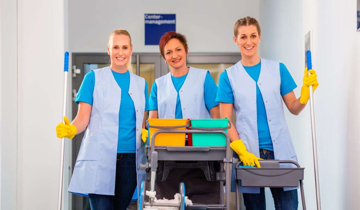 Team of cleaning ladies in Limassol wearing uniforms and holding cleaning tools in a hallway.